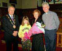 Brownie Guide Lucy McDonald presents a bouquet of flowers to the Mayoress - Mrs Laureen Lunn welcoming her and the Mayor to the Girl Guides’ Thinking Day Service in Lisburn Cathedral.  Looking on is the Mayor - Councillor Trevor Lunn and the rector, the Rev Canon Sam Wright (right).